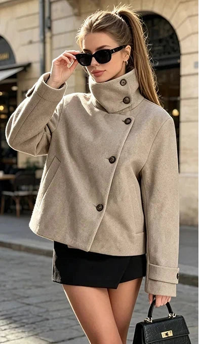 A woman wearing a beige high-neck button-front jacket with a shawl collar, styled with a black skirt, black boots, and a black handbag, standing on a city street. On the right, a row of small thumbnails shows the jacket in multiple colors: black, beige, light pink, gray, navy, burgundy, and brown.